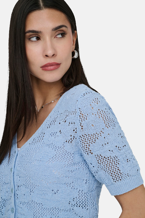 Gilet bleu en maille ajourée de ONLY, porté avec un collier discret et des boucles d'oreilles argentées.
