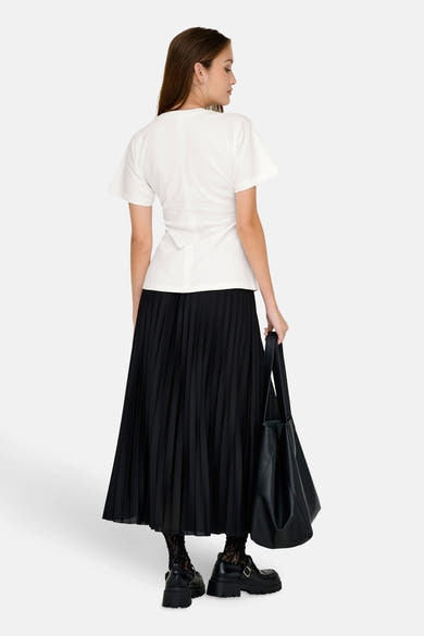 Top uni manches courtes blanc de ONLY®, porté avec une jupe plissée noire, un sac noir et des chaussures plateforme.