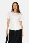 Top uni manches courtes blanc de ONLY®, porté avec une jupe plissée noire et un sac noir.