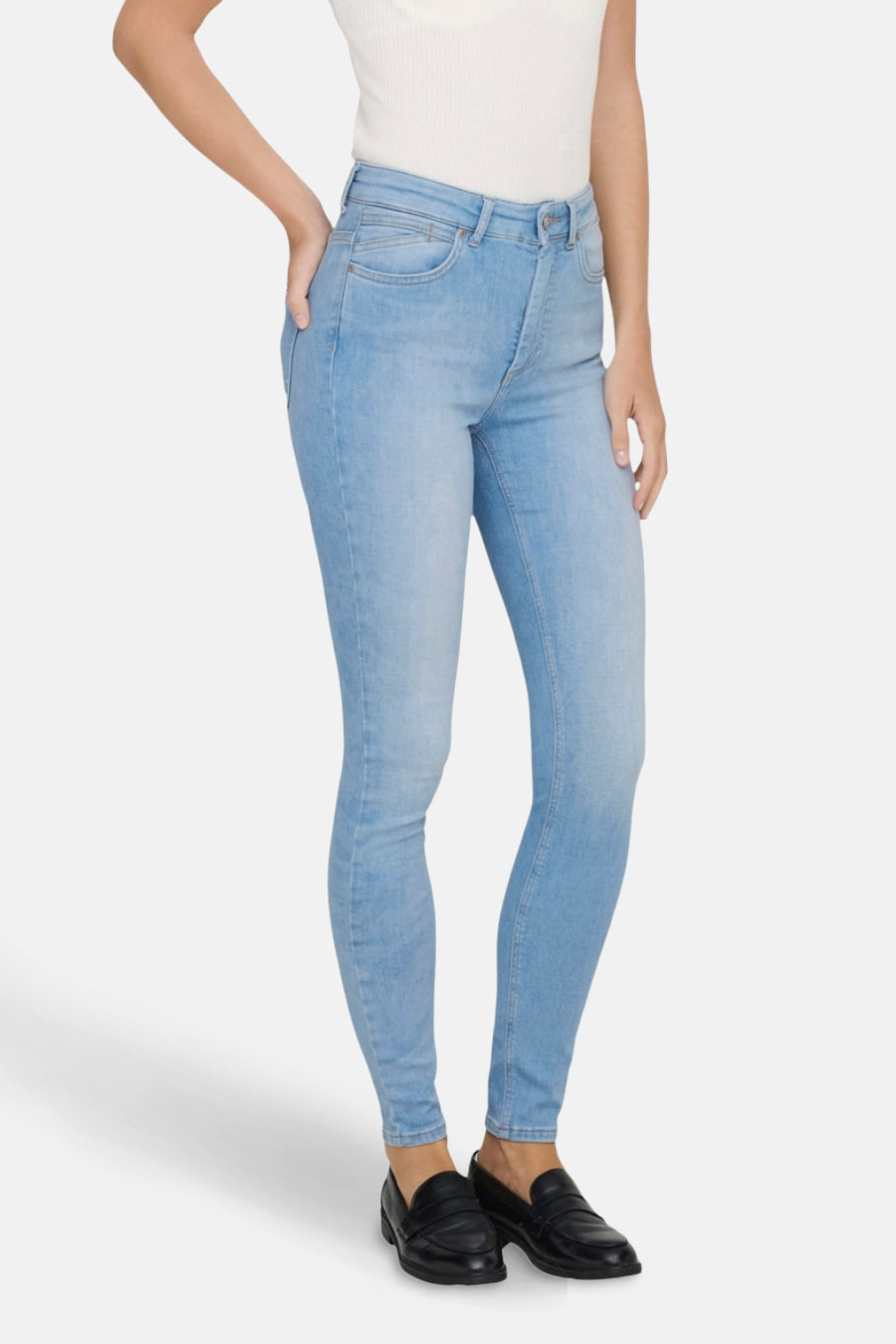 Lichtblauwe skinny jeans van ONLY, gedragen met een witte top en zwarte schoenen.