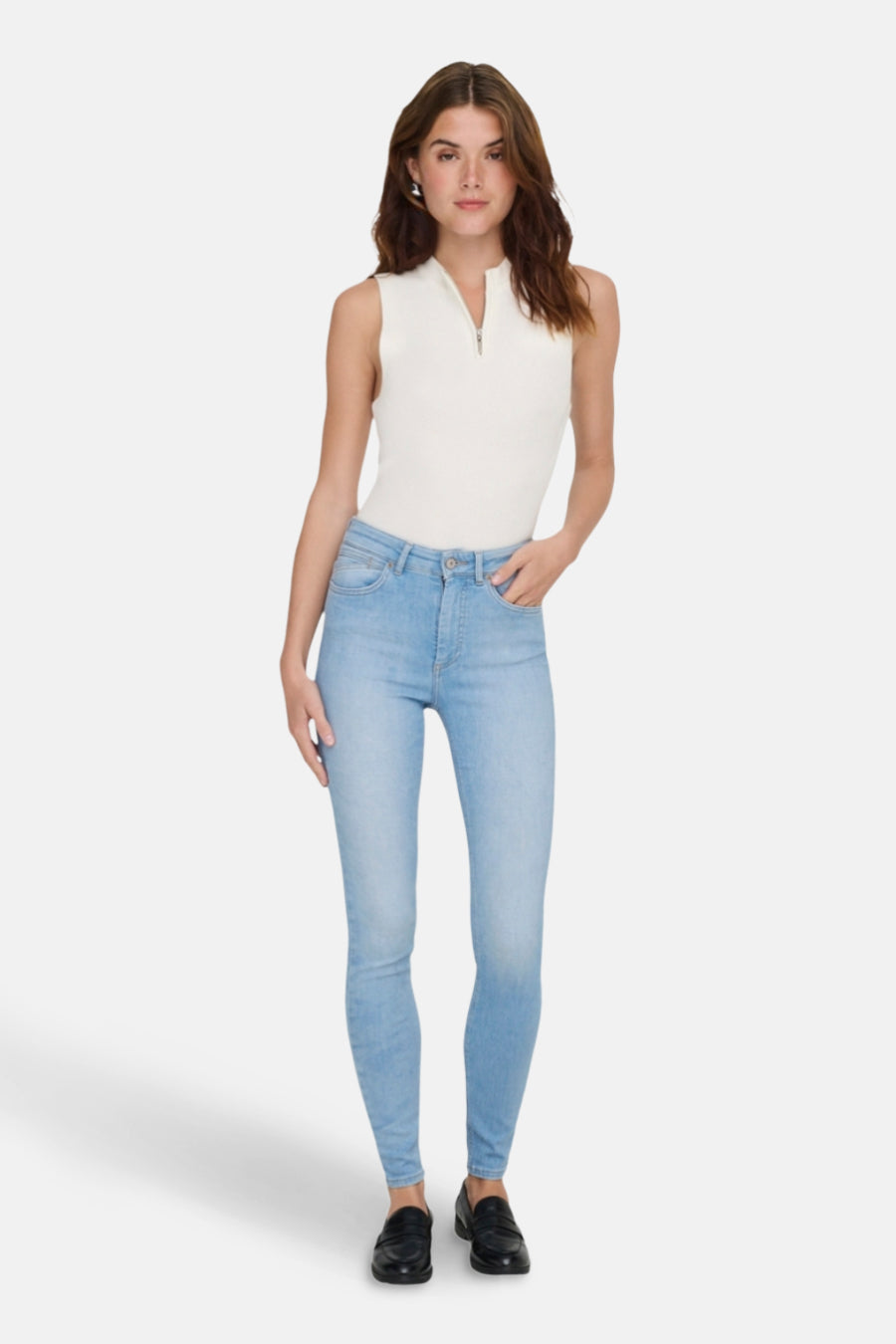 Jean skinny bleu clair de ONLY, porté avec un top blanc et des chaussures noires.