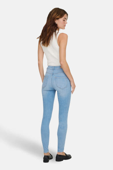 Skinny jeans in lichtblauw denim van ONLY, gedragen met een witte top en zwarte loafers, achterzijde.