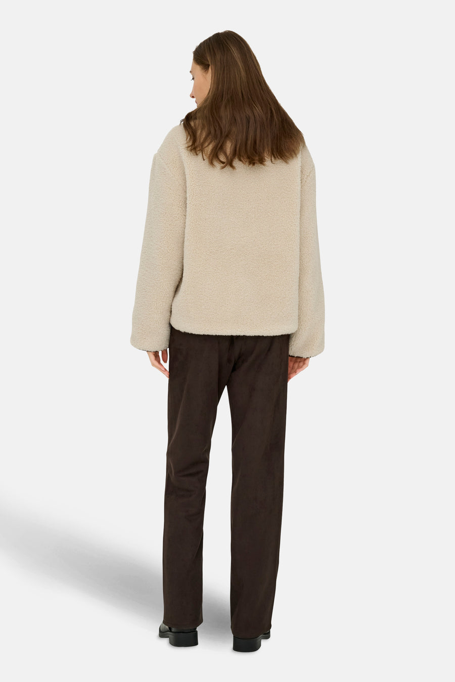 Veste courte écru de JDY, avec une texture bouclée, portée avec un pantalon marron.