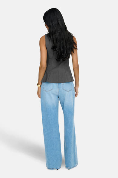 Grijze ONLY® blouse met peplum-snit, gedragen met een wijde high-waist jeans en een gouden armband.