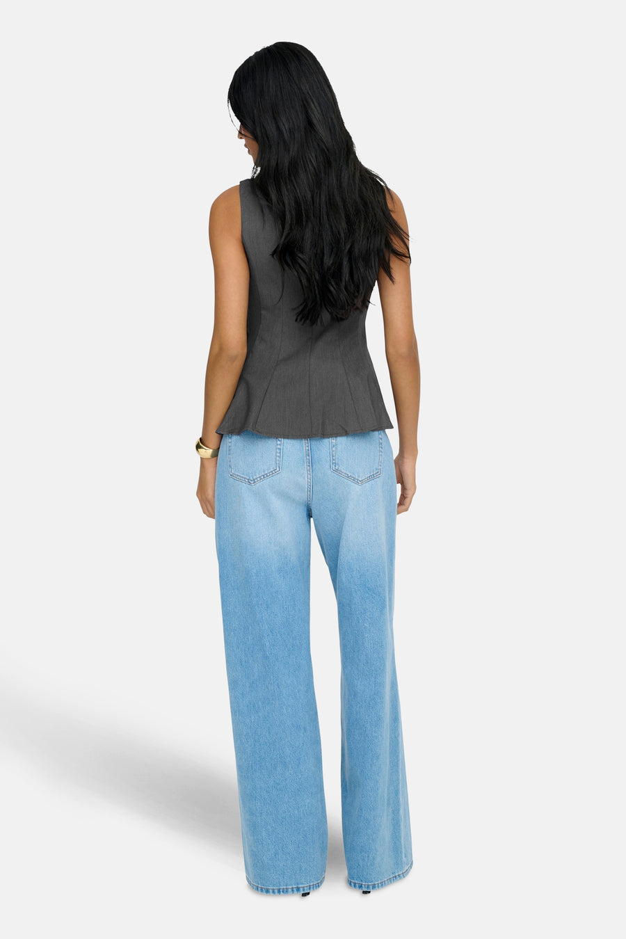 Grijze ONLY® blouse met peplum-snit, gedragen met een wijde high-waist jeans en een gouden armband.