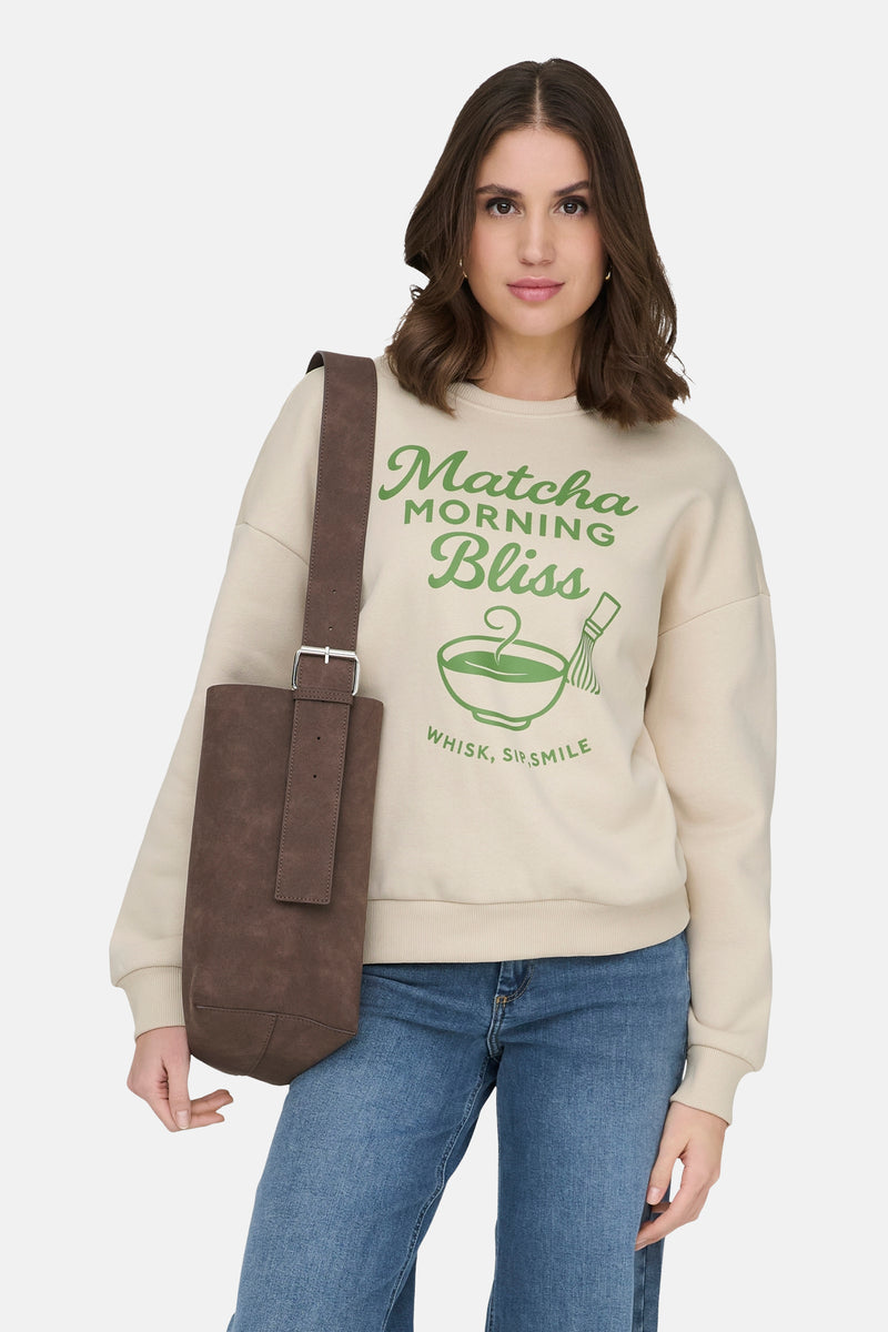 Ecru sweatshirt van ONLY®, met Matcha print, gedragen met een wijde jeans en zwarte enkellaarsjes.