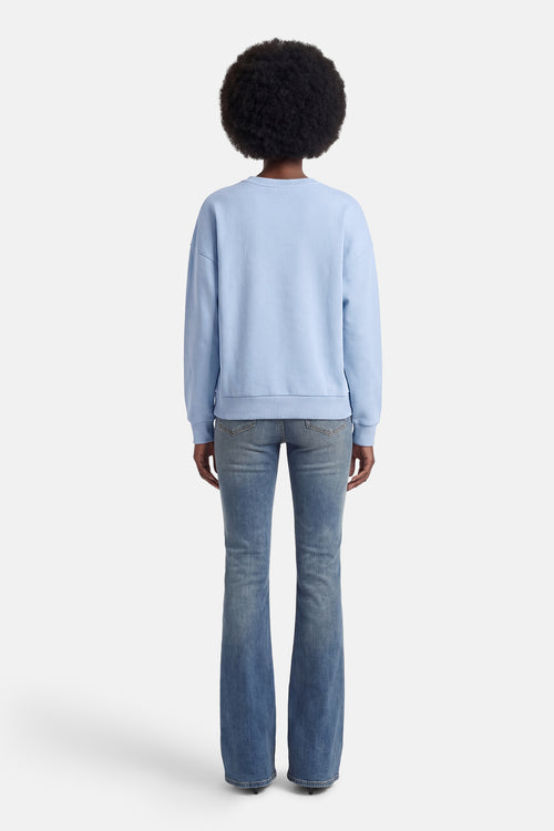 Sweat bleu de ONLY, avec une coupe décontractée, porté avec un jean évasé.
