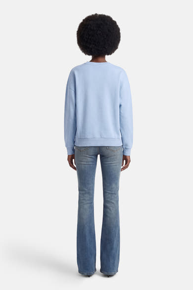 Sweat bleu de ONLY, avec une coupe décontractée, porté avec un jean évasé.
