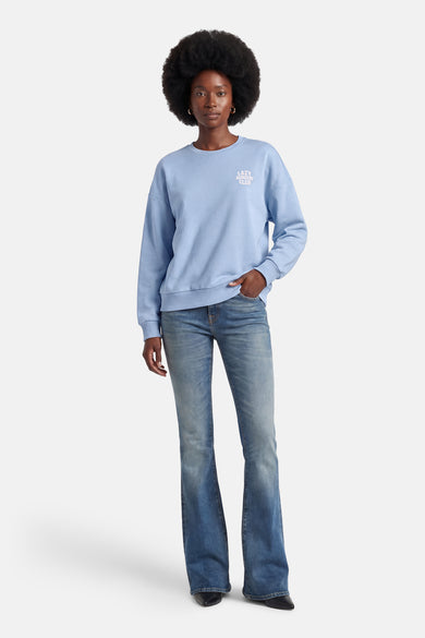 Blauwe trui van ONLY, met de tekst "Lazy Sunday Club", gedragen met een wijde jeans en zwarte schoenen.