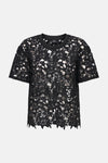 T-shirt noir en dentelle par JDY, avec motif floral ajouré et bordure festonnée.