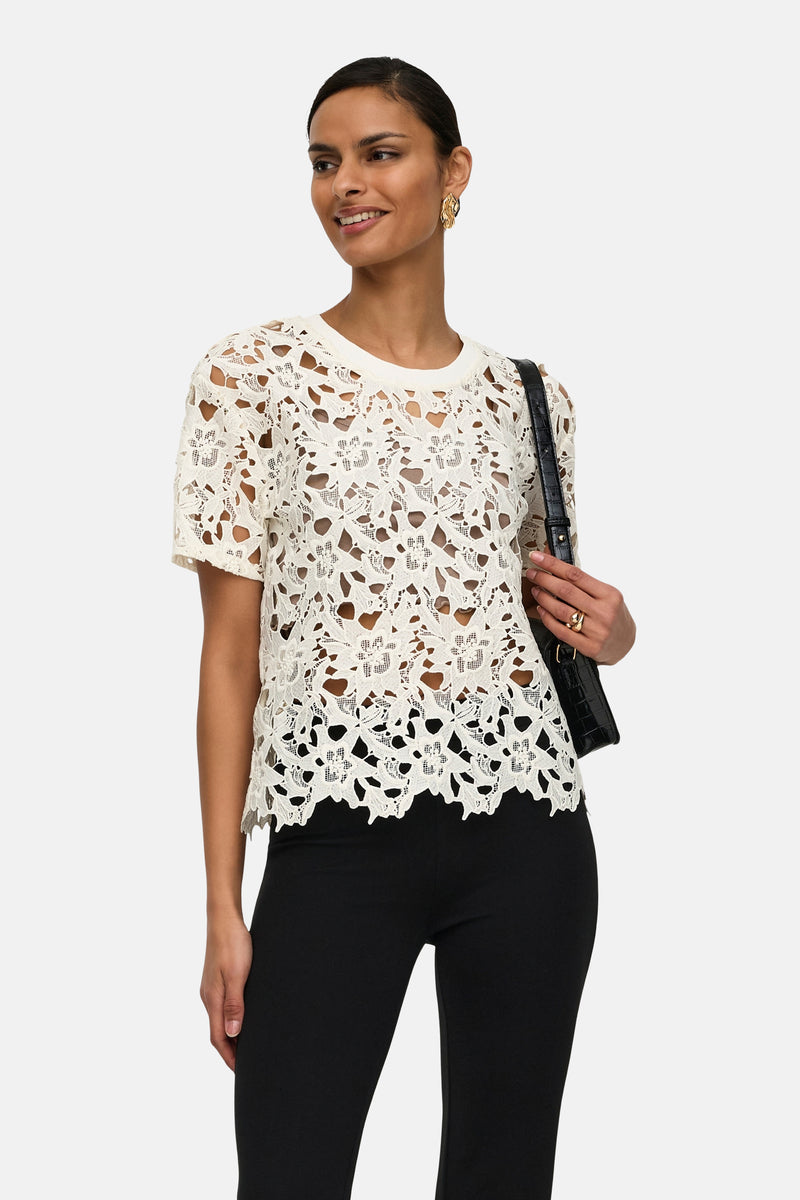 T-shirt en dentelle blanc de JDY, porté avec un pantalon noir et un sac à main noir.