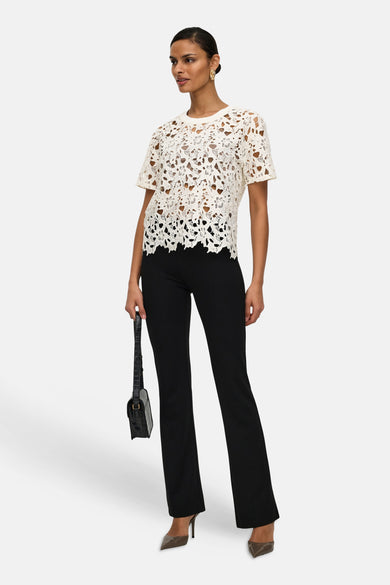T-shirt blanc en dentelle de JDY, porté avec un pantalon noir et des escarpins à talons aiguilles.