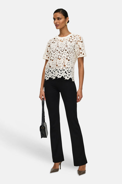 T-shirt blanc en dentelle de JDY, porté avec un pantalon noir et des escarpins à talons aiguilles.