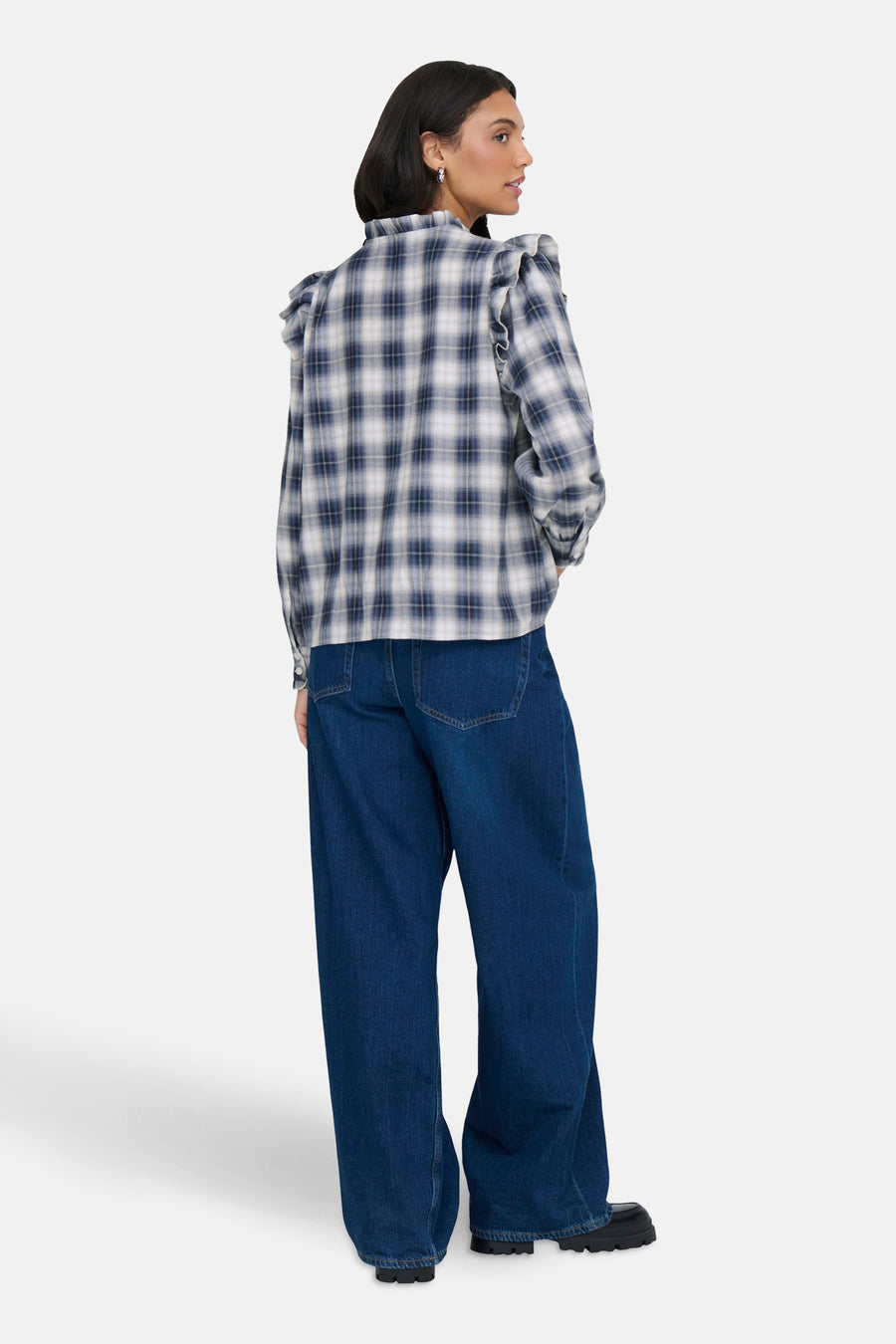 Chemisier bleu à carreaux by ONLY®, avec manches longues à volants, porté avec un jean ample bleu.
