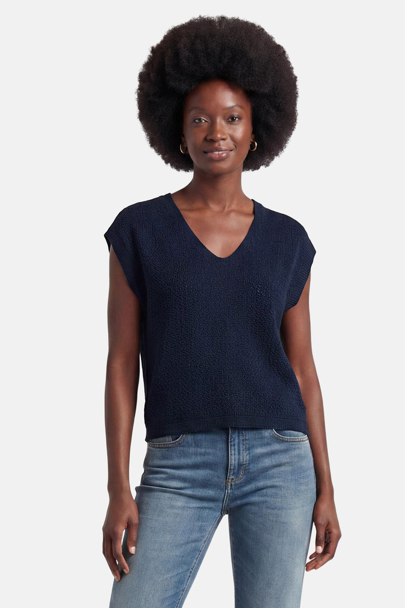 Blauw T-shirt van JDY, achterkant, met gebreide textuur en knopen langs de rug, gedragen met een spijkerbroek en zwarte muiltjes.