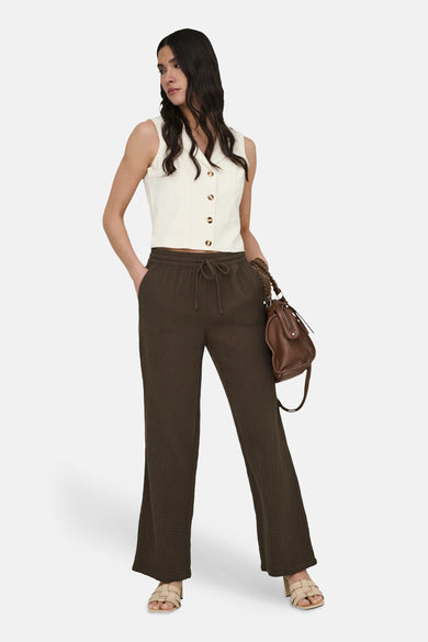 Blazer beige de JDY, sans manches, boutonné sur le devant, porté avec un pantalon marron et un sac à main en cuir.