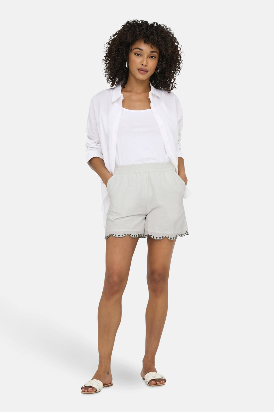 Kort wit topje van JDY met geschulpte zoom en uitgesneden details, gedragen met een witte blouse en een wit hemdje.