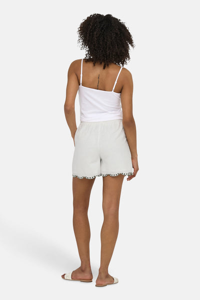 Short blanc de JDY, avec ourlet festonné brodé de petits points décoratifs, porté avec un débardeur blanc et des sandales.
