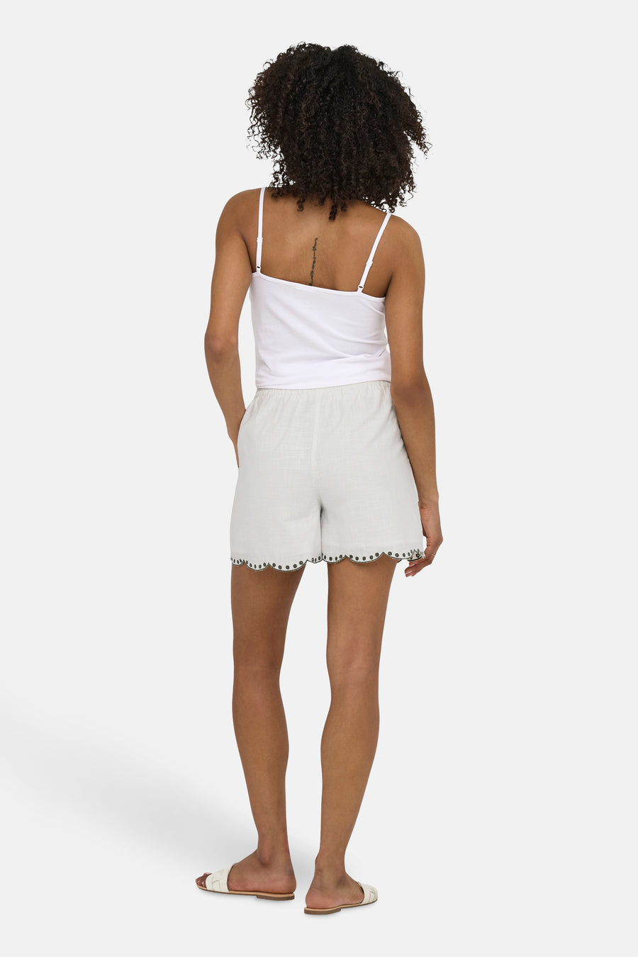 Kort wit hemdje van JDY, met een geschulpte zoom geborduurd met kleine decoratieve steken, gedragen met een witte tanktop en sandalen.