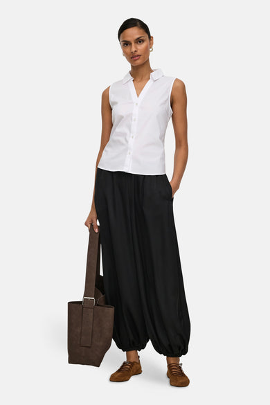 Chemisier blanc sans manches de JDY, porté avec un pantalon noir ample et un sac marron.