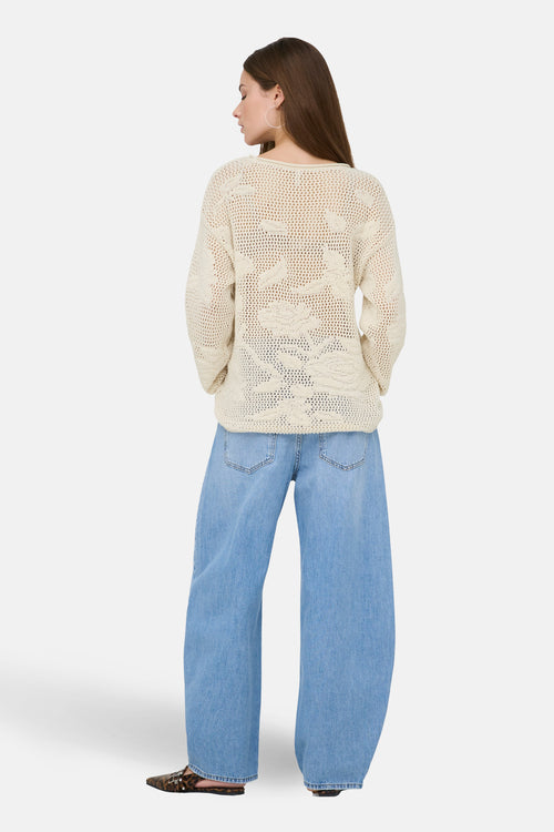 Pull à col rond écru de ONLY, avec motifs ajourés texturés, porté avec un jean ample bleu clair.