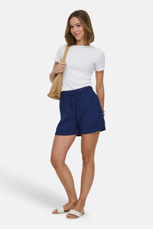 Short en denim bleu foncé de ONLY, porté avec un t-shirt blanc et des sandales tissées.