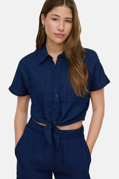 Chemisier bleu à manches courtes de ONLY, noué à la taille, porté avec un pantalon assorti.