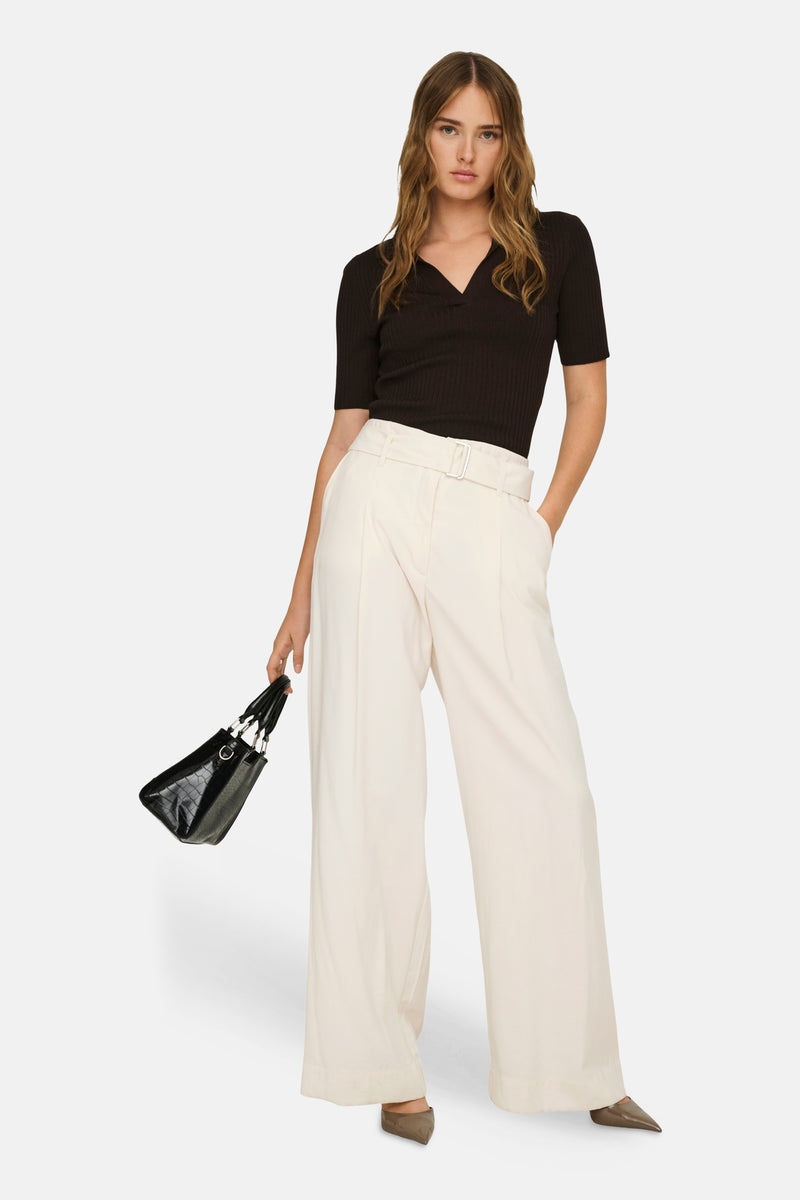 Beige wijde broek van ONLY®, hoge taille, met riem en zilveren gesp, gedragen met een zwarte top en tas.