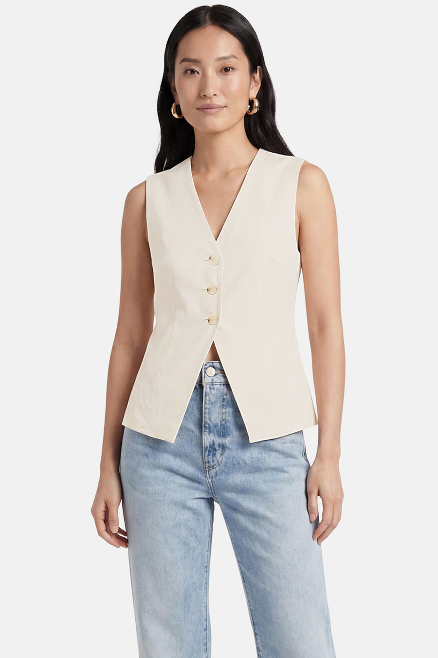 Blazer beige sans manches de ONLY® à col V, fermé par trois boutons, associé à un jean clair et des créoles dorées.