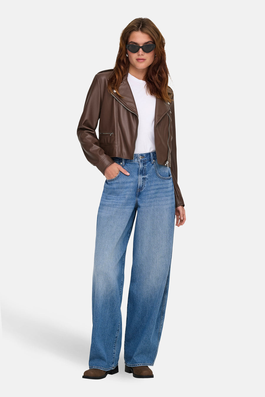 Jeans bleu clair de ONLY®, portés avec une veste en similicuir marron et un t-shirt blanc.