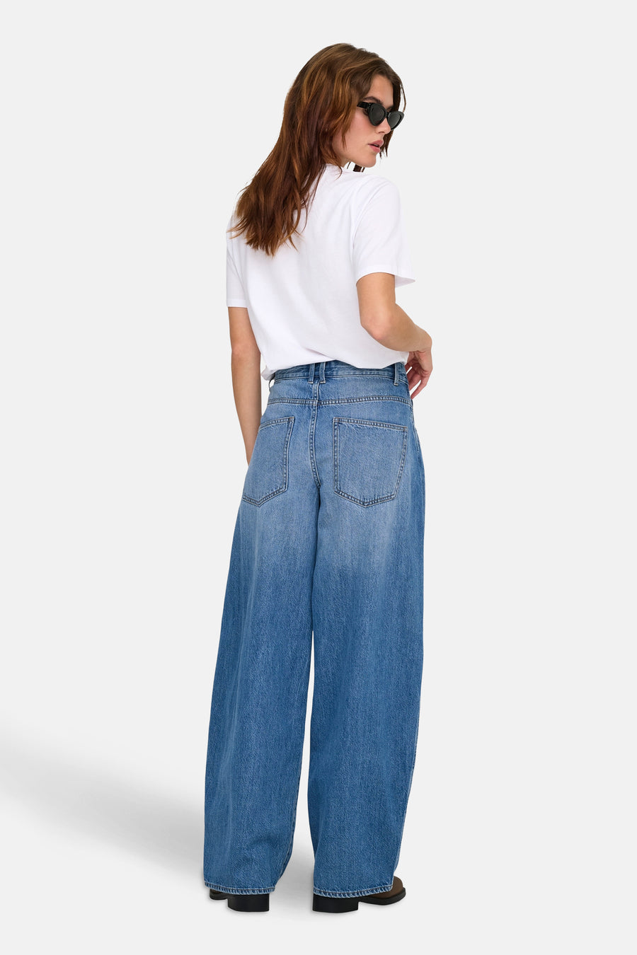 Jean ample bleu clair de ONLY®, porté avec un t-shirt blanc et des lunettes de soleil.