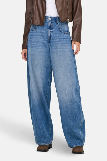 Wijde spijkerbroek in lichtblauw denim van ONLY, gedragen met een bruin jasje en enkellaarsjes.