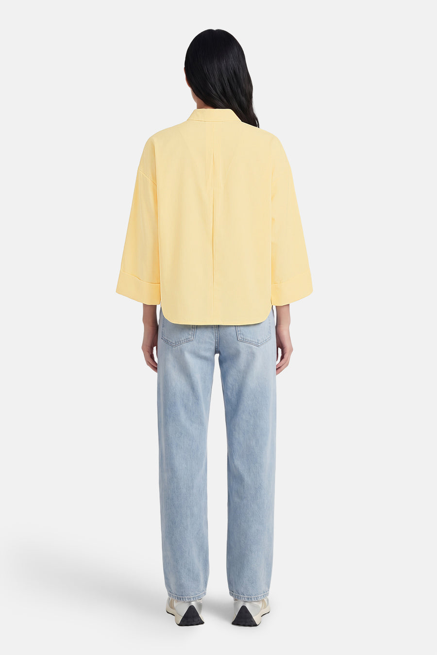 Chemise à manches longues jaune, de ONLY®, portée avec un jean bleu clair et des baskets blanches, vue de dos.
