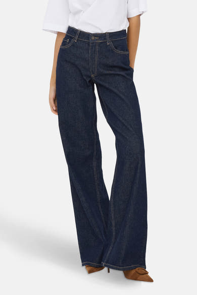 Wijde jeans in donkerblauw denim van JDY, gedragen met een wit T-shirt en bruine schoenen.