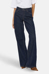 Wijde jeans in donkerblauw denim van JDY, gedragen met een wit T-shirt en bruine schoenen.