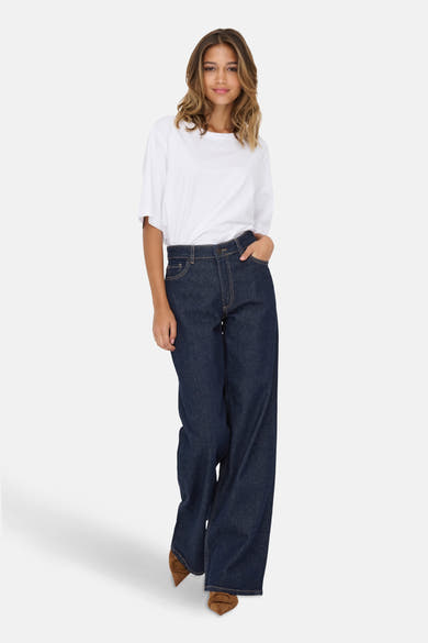 Jean large en denim bleu foncé de JDY, porté avec un t-shirt blanc et des chaussures marron.

