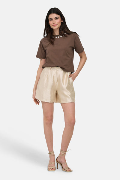 Short doré de ONLY®, à la texture brillante, porté par une femme avec des talons lacés.
