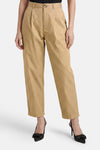 Pantalon beige de ONLY®, plissé sur le devant avec fermeture boutonnée et ourlets retroussés, porté avec des escarpins noirs à nœud.