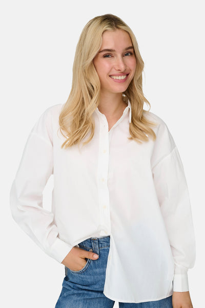 Chemisier blanc à manches longues de ONLY, porté avec un jean, femme souriante.