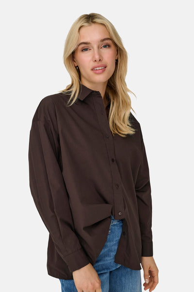 Chemisier brun à manches longues de ONLY®, porté avec un jean en denim bleu.
