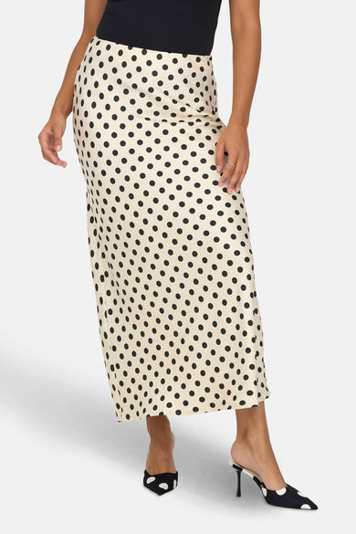 Middelhoogse ecru rok met zwarte stippen van ONLY, gedragen met een zwart tanktop en hoge sandalen.