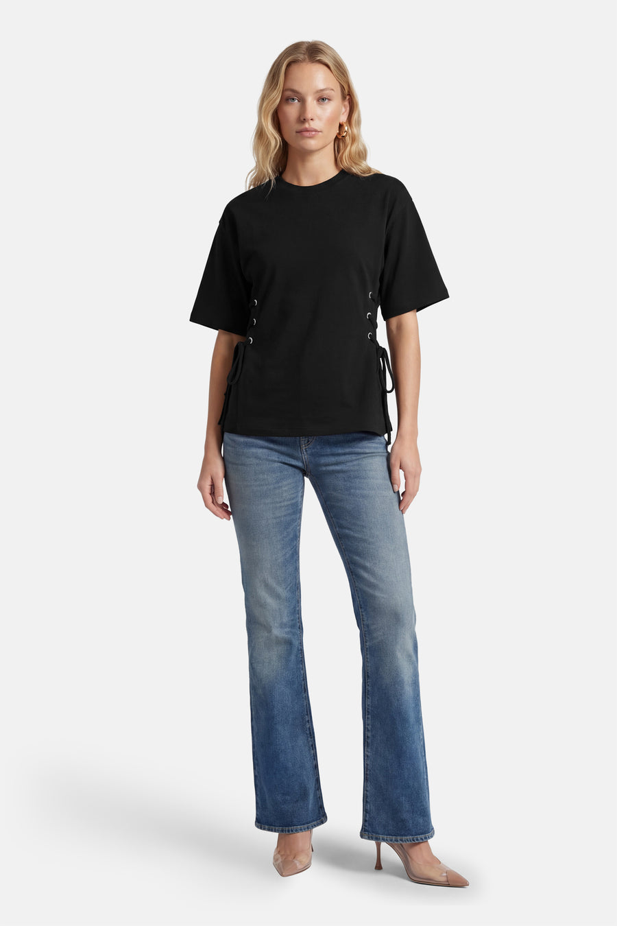 T-shirt noir à manches courtes de ONLY®, avec des lacets décoratifs sur les côtés, porté avec un jean bleu et des escarpins nude.
