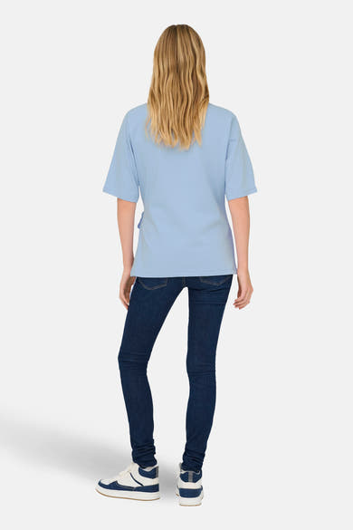 T-shirt bleu à manches courtes de ONLY, porté avec un jean foncé et des baskets blanches.