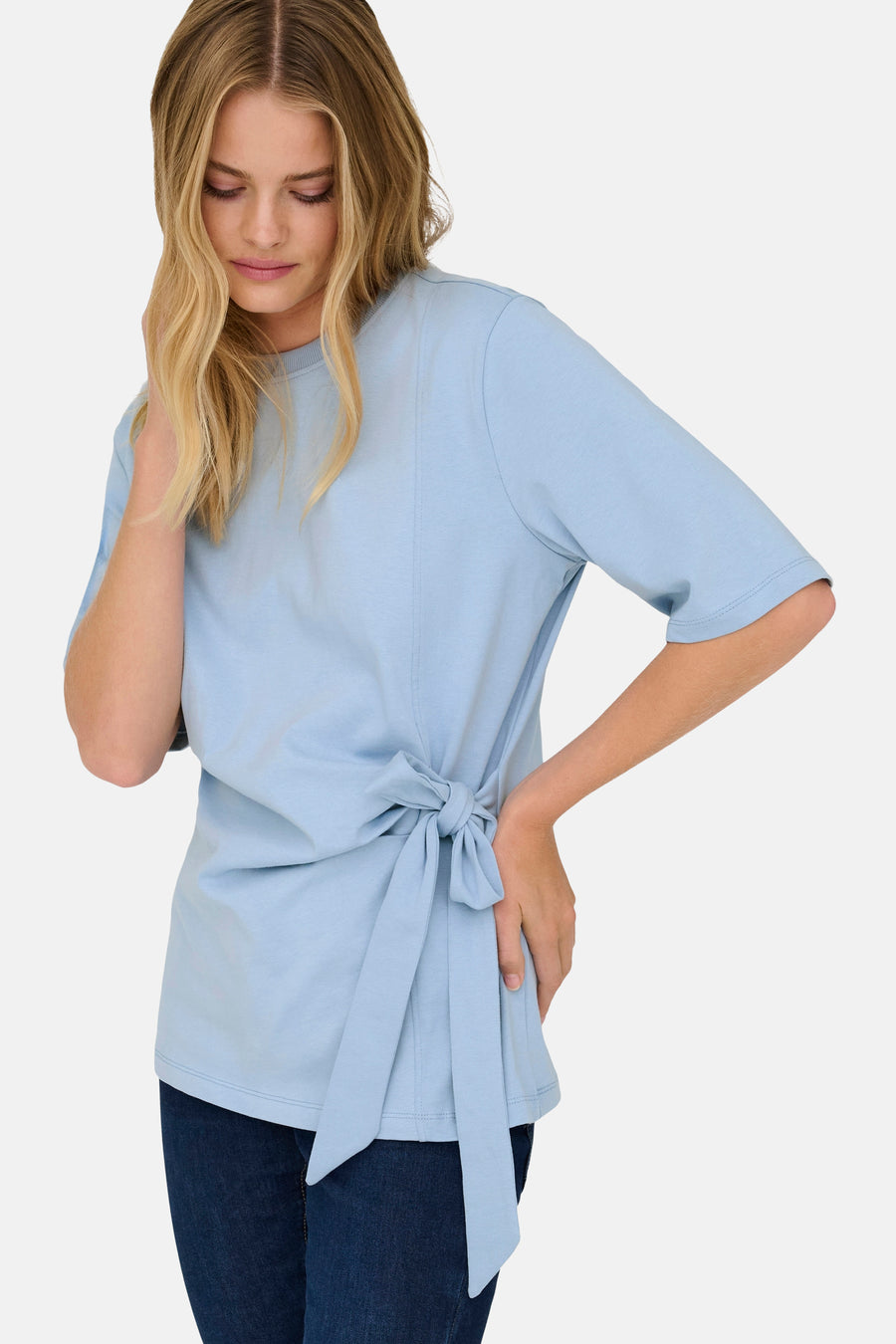 T-shirt bleu à manches courtes de ONLY®, noué sur le côté, porté avec un jean.