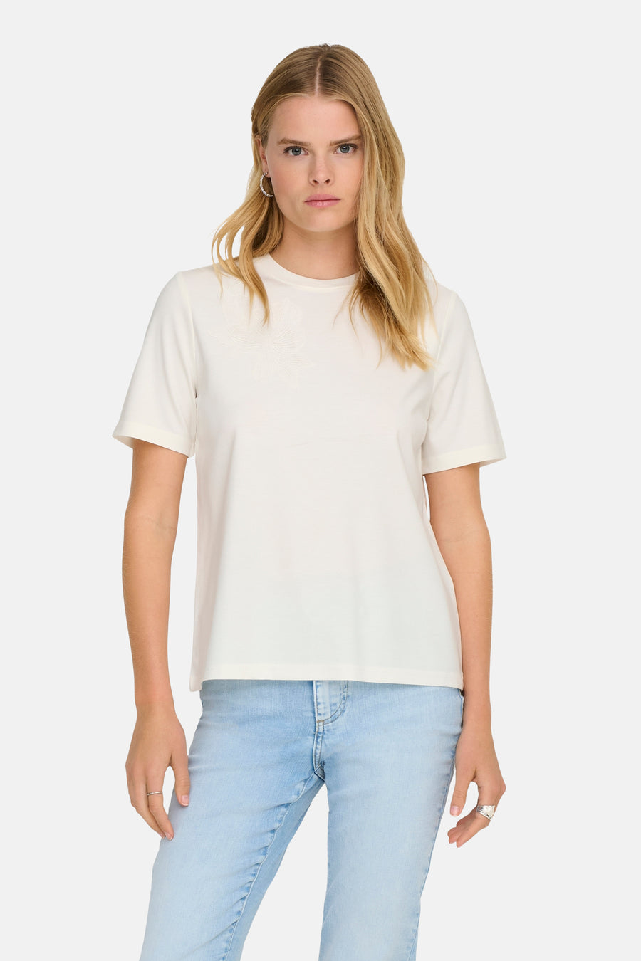 T-shirt uni à manches courtes, blanc par ONLY®, avec un motif floral délicat. Porté avec un jean clair.