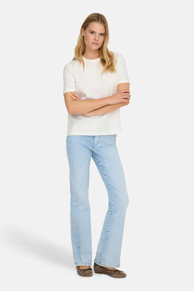 T-shirt uni blanc à manches courtes de ONLY®, porté avec un jean bleu clair et des ballerines marron.
