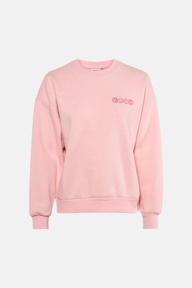 Roze sweatshirt van ONLY®, met decoratieve tekst, gedragen met een grijze jeans en hoge hakken.