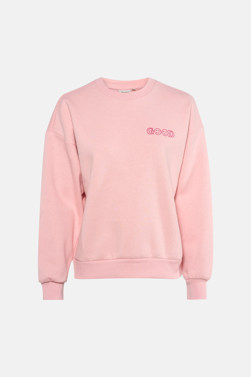 Roze sweatshirt van ONLY®, met decoratieve tekst, gedragen met een grijze jeans en hoge hakken.