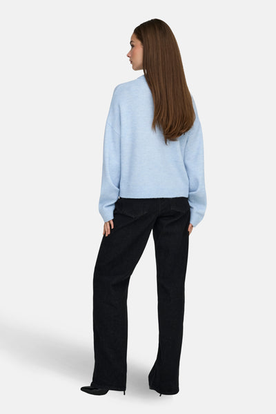 Pull col rond bleu de ONLY®, porté avec un pantalon noir taille haute et des escarpins noirs, vue de dos.
