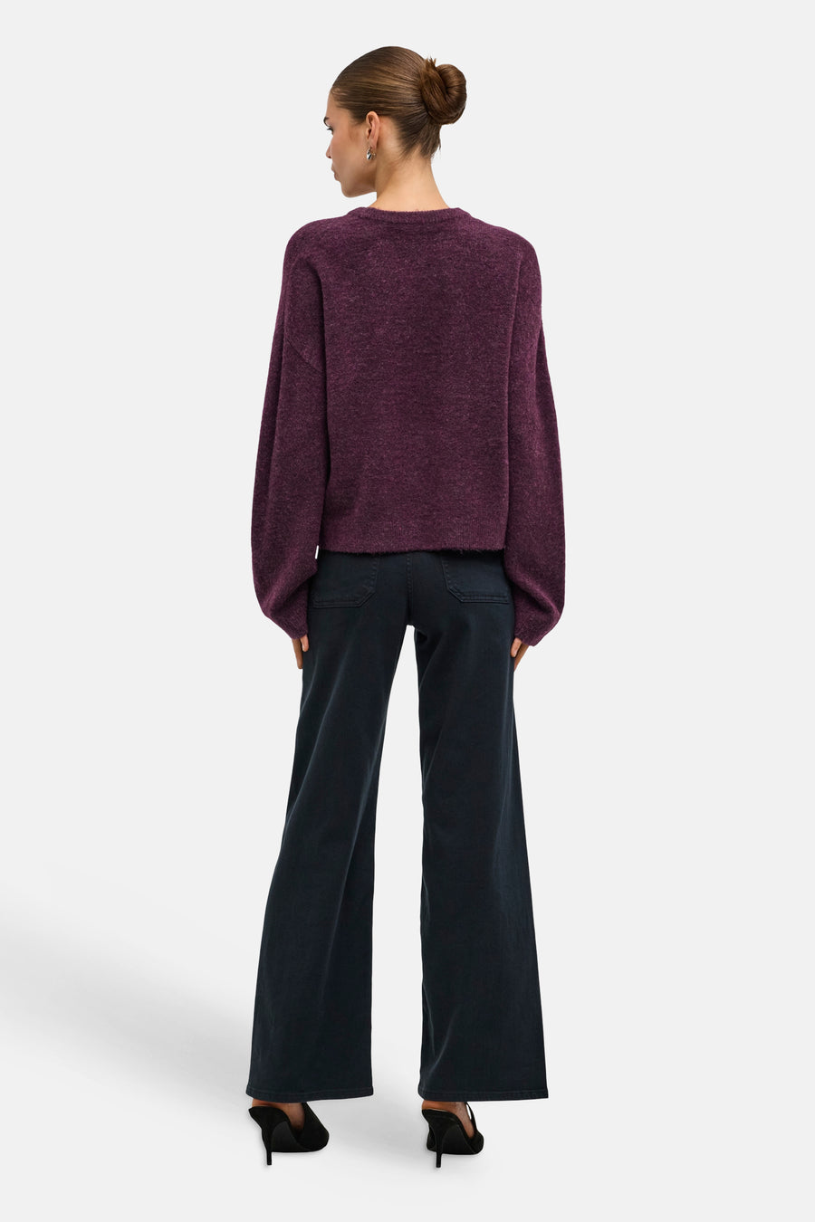 Mauve wine O-neck sweater with textured knit and loose fit, back view on model wearing dark flared jeans and black heels